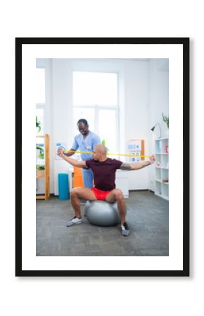 Physical therapist smiling while working with sportsman