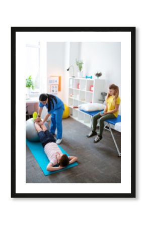 Good-looking doctor in blue uniform correcting movements