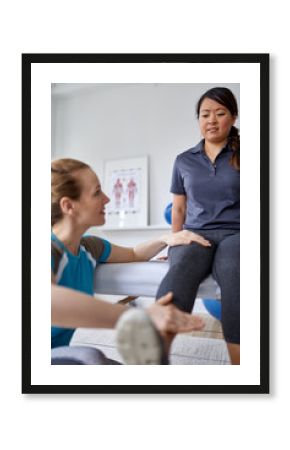 Caucasian woman physiotherapist strectching the leg and knee of a mid-adult chinese female patient sitting on a massage table