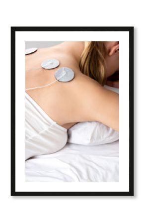 Cropped view of woman lying on massage couch during electrode treatment of back isolated on grey