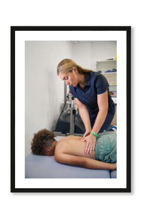 Female physiotherapist works on the back of a young patient