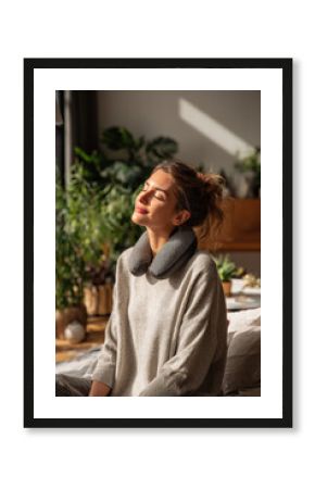 Relaxed woman with neck massager sitting indoors warm daylight wellness health care routine, Selective Focus..