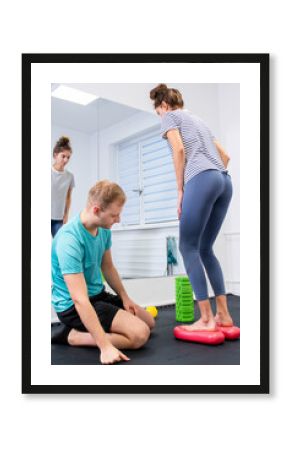 Woman with ankle pain in physical therapy. Physical therapist exercising with female patient in front of a large mirror.