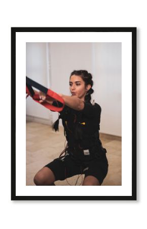 A girl exercising with an electrostimulation vest in a clinic.