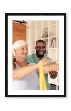 African american male physiotherapist helping senior woman to exercise with resistance bands