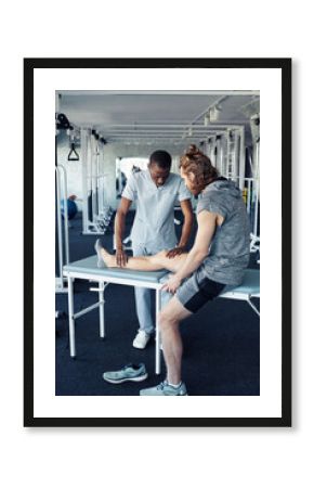 African young therapist massaging leg of patient before sport training in gym