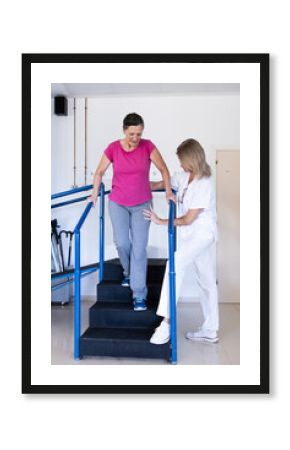 Vertical photo of a middle aged brunette woman in pink shirt. She is doing rehabilitation with her physiotherapist who is helping her.