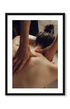 Hands of female chiropractor massaging shoulders of young woman lying on massage table. Concept of physical therapy treatment ,neck pressure point