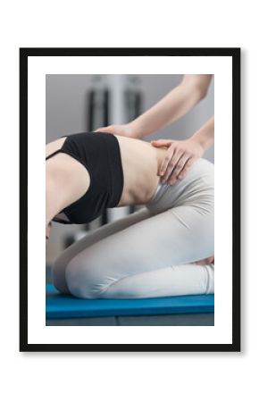 Individual lesson of physical therapy with rehabilitation specialist. Back rehabilitation. Physiotherapist working with patient on carpet. Personal training in Pilates, stretching, yoga. Side view.