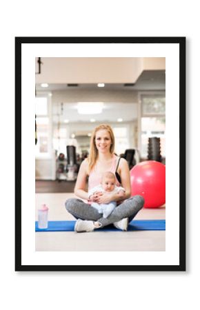 Portrait of new mom on group exercise class in gym. Moms staying active while boding with babies.