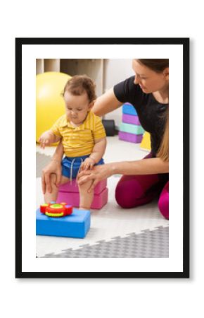 Birth trauma rehabilitation. Physical therapist assisting baby patient with motor skill development during therapy session