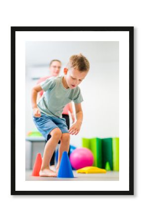 Young boy exercising with female physical therapist during therapy session. Child occupational physical therapy. Bilateral coordination.