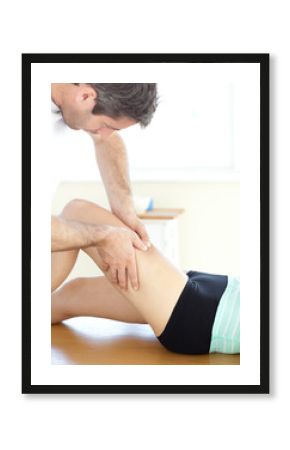 Handsome young physical therapist giving a leg massage