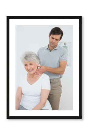 Male physiotherapist massaging a senior woman's neck