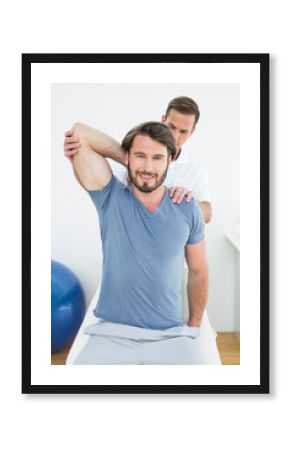 Male physiotherapist stretching a smiling young man's arm