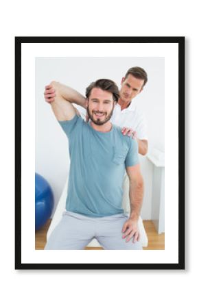 Male physiotherapist stretching a smiling man's arm