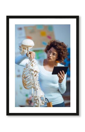 Medical doctor woman teaching anatomy using human skeleton model