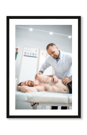 Professional senior physiotherapist doing manual treatment to a man in the cabinet of rehabilitation clinic