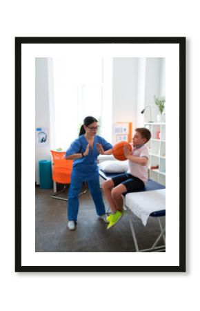 Helpful Asian physical therapist working with little boy