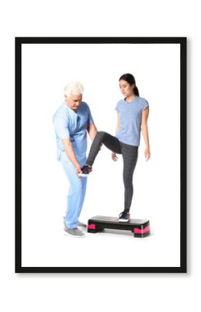 Mature physiotherapist working with young Asian woman on white background