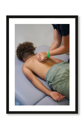 Experienced physiotherapist works on the back of a young patient