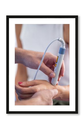 Physical therapist performs laser therapy on a patients wrist, targeting pain relief and promoting healing in a clinical setting