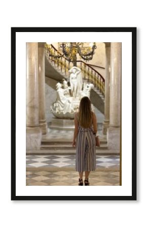Vertical shot of a woman looking at a sculpture in the Revoltella Museum