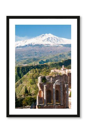 View of some columns in the stage of the greek theater in Taormina and a perspective of snowy mount Etna