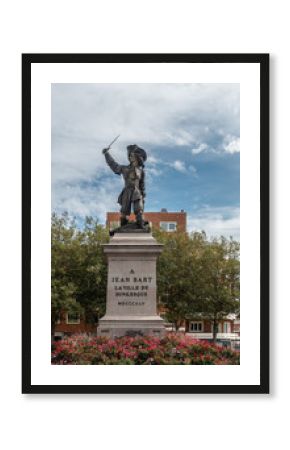 Dunkerque, France - September 16, 2018: Jean Bart, famous Pirate, on his square in Dunkirk with red flowers in front under blue sky with white clouds. Green tree background.
