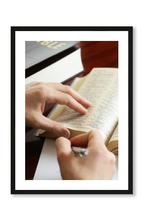 Detail of hands with pen and open Bible