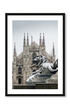 Falling snowflakes at ornate of lion on Piazza del Duomo in Milan, Lombardy, Italy. The Patron Saint of Milan, Madonnina, is visible above the Duomo Cathedral, with copy space