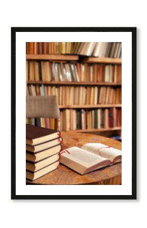 Table with a book and book pile in front of a shelf full of books