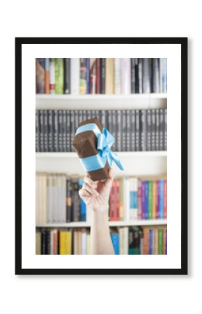 hand with brown present box over library