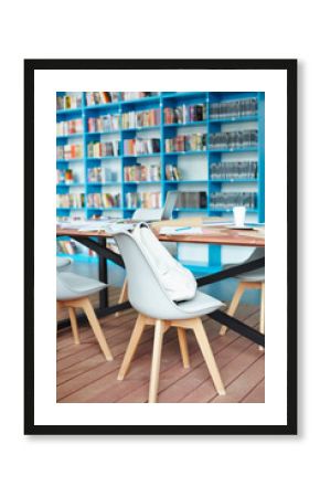 One of armchairs with white leather rucksack by table in library of modern college or university