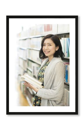 図書館で本を持ち微笑む女性