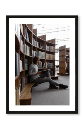Student with book at bookcase in library