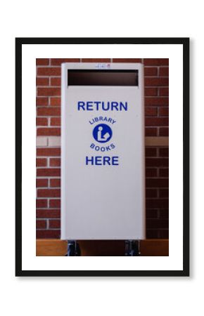 White library book return bin with the words "Return Library Books Here" on the front.