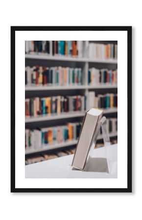 Close-up of a book displayed on a stand with a blurred background of library shelves. Concept of literature, knowledge