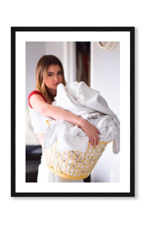 Young girl carrying a basket full of laundry with a look of annoyance on her face