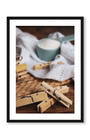 Wooden clothespins, scoop of laundry powder and fabric on table, closeup
