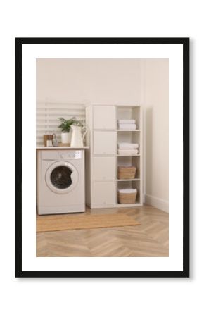 Laundry room interior with modern washing machine and shelving unit near white wall
