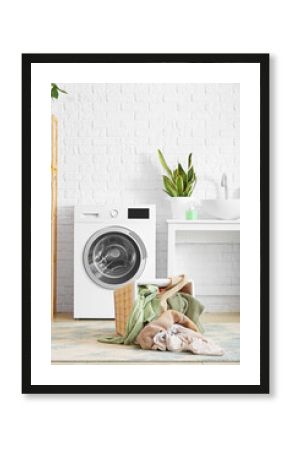 Basket with dirty clothes near washing machine in laundry room