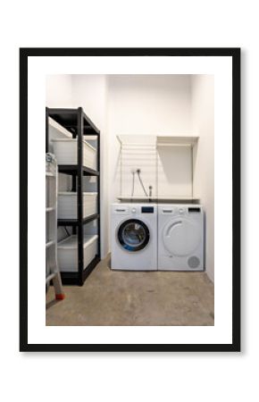 Interior of a storeroom with modern washing machine, dryer machine, foldable ladder, shelf with tools and boxes.