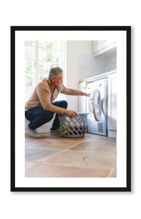 Happy caucasian man standing in kitchen and doing laundry