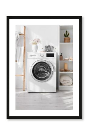 Modern washing machine and shelf unit with bath accessories near white wall