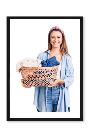 Young beautiful girl holding laundry basket looking positive and happy standing and smiling with a confident smile showing teeth