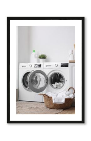 Modern washing machines with dirty clothes in laundry room