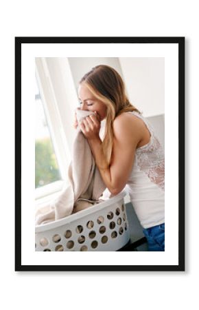 Young, woman and clothes smell laundry in basket is happy cloth is clean in the kitchen in apartment. Female person, fabric scent and cleaning for housework with happiness at home in a laundry room.