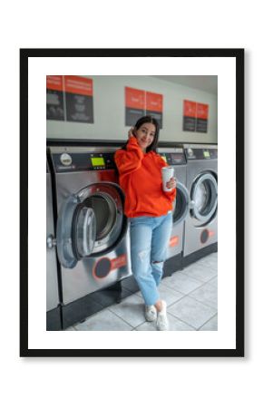 Portrait of young woman standing in the self-service public laundry.