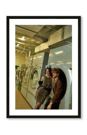 trendy young multiethnic couple in modern outfits posing in public laundry in evening